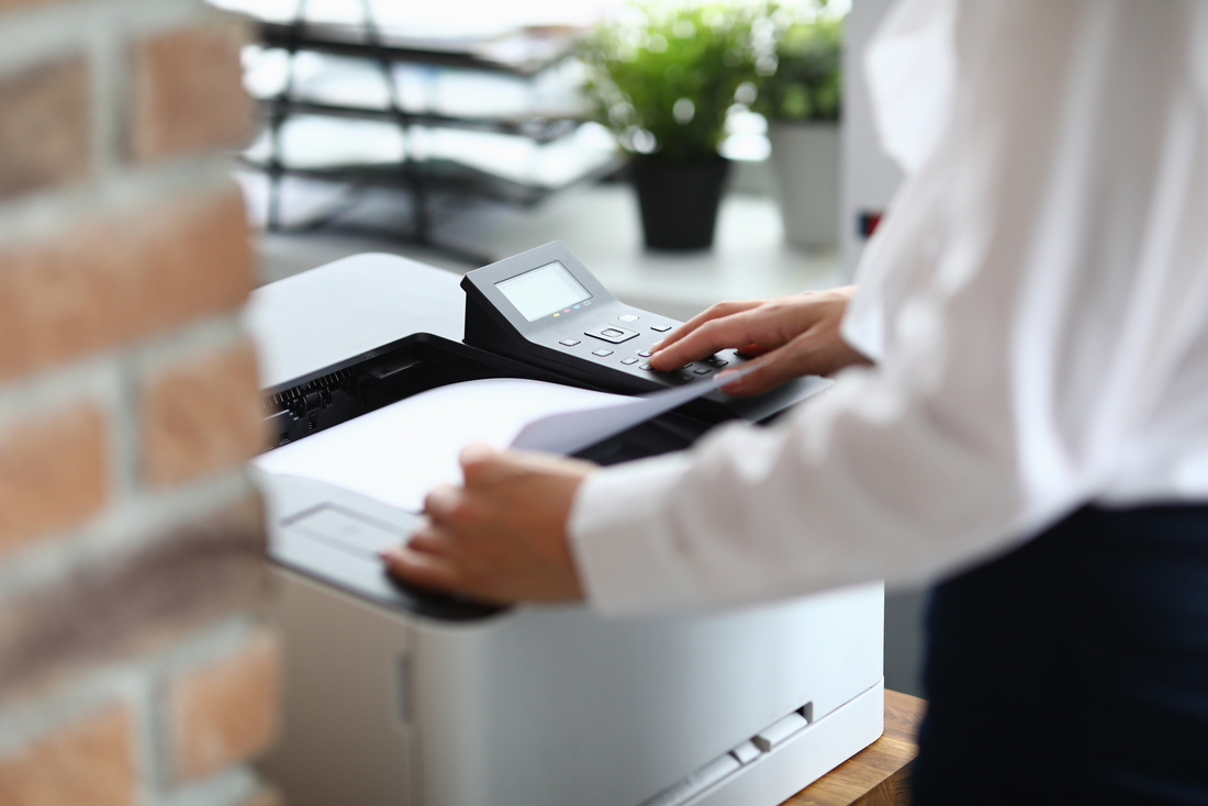 Woman in office prints documents on printer. Scanning documents at workplace concept Woman in office prints documents on printer